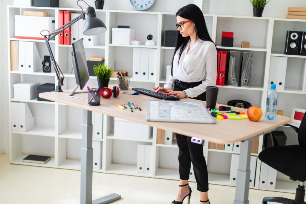 adjustable standing desk with office worker standing at it